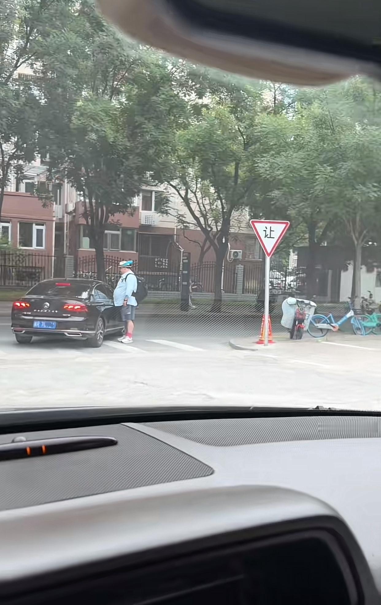 近日北京，一辆黑色轿车在路口右转，一名外国人走在人行横道线上过马路，可就在轿车右