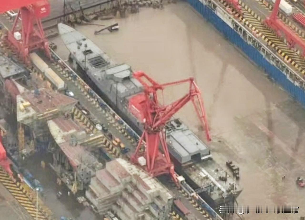 这是开始批量生产054B型护卫舰，现场可见的大型龙门起重机、模块化舰体部件、脚手