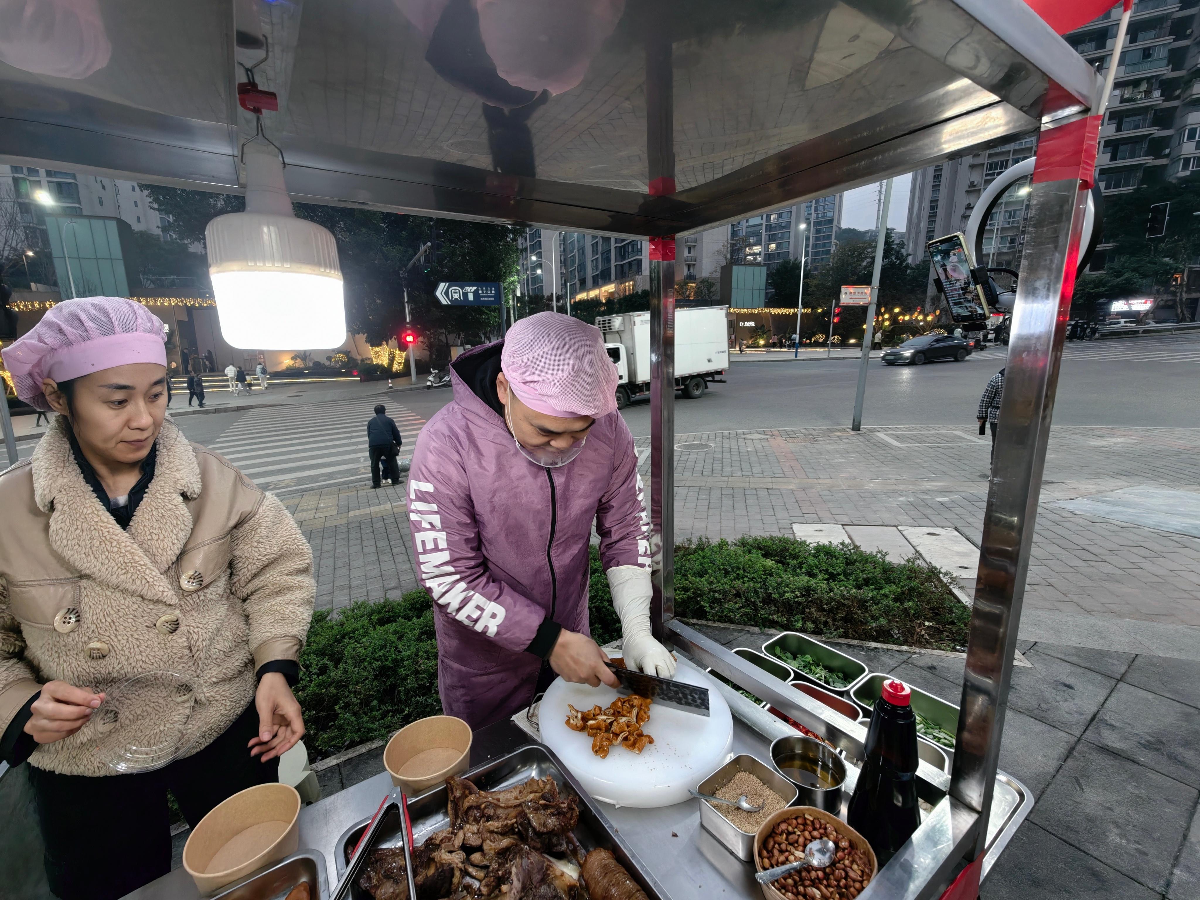 接孩子，看起来挺好吃，就顺路买个肥肠老两口一边卖熟食一边还在直播…我看直播间人挺