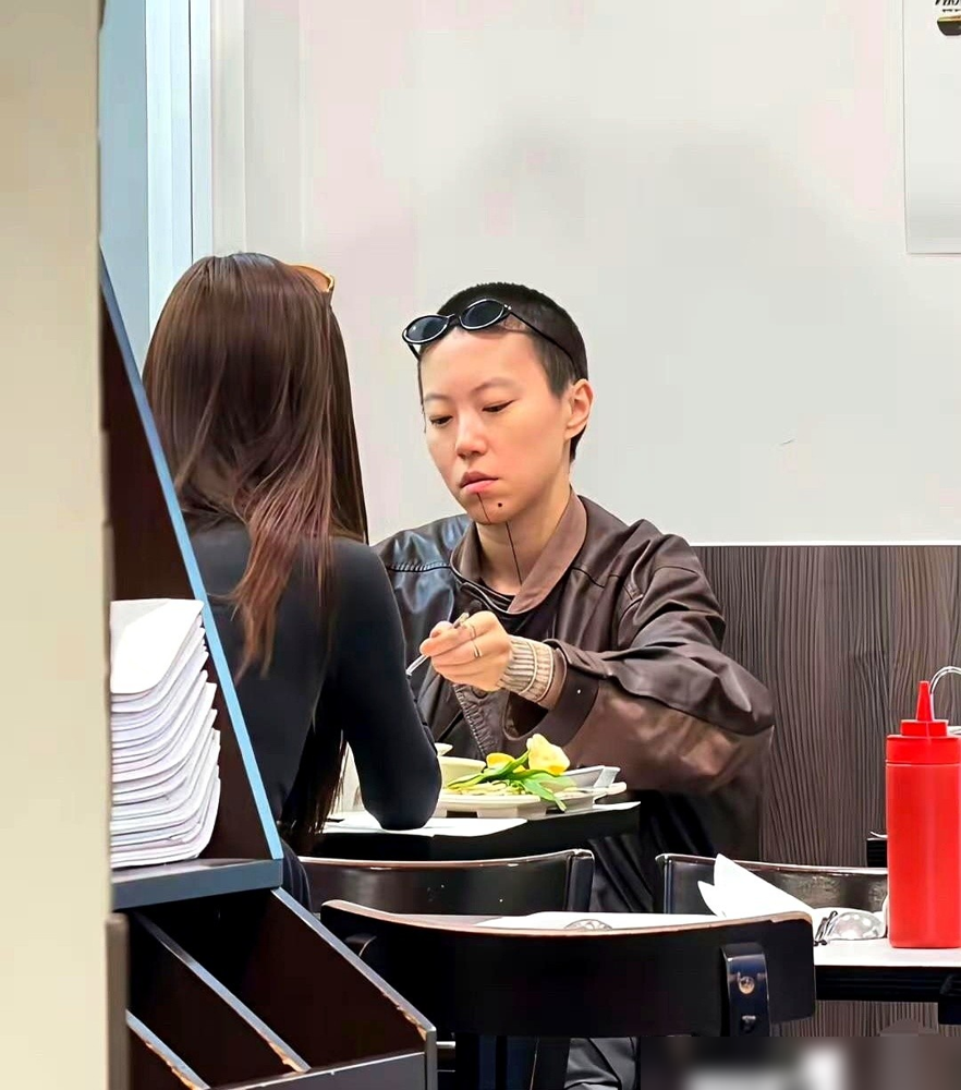 窦靖童跟一姑娘在街边小馆，头碰头分一碗河粉，吃得旁若无人。她下巴那块洗淡了的纹身没遮没掩，坐那跟普通