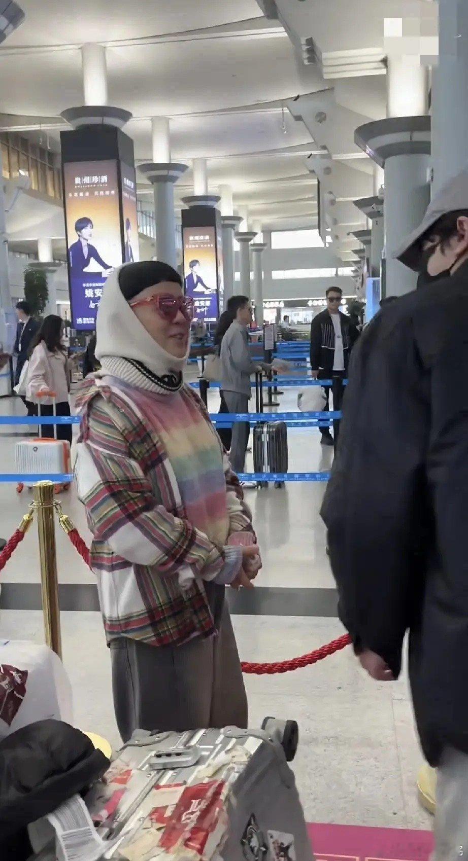 金龟子独自现身机场裹了个毛线围脖，脸比较老，竟然像是金龟子奶奶，个子好矮，与对面