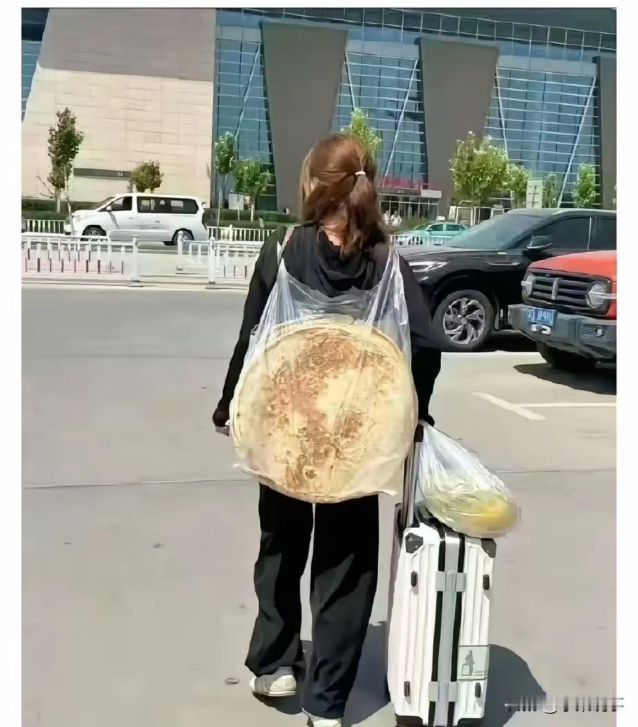 深圳机场外一女孩背着两个大饼和一个哈密瓜走出机场，成为一道风景。哈密瓜我见过，但