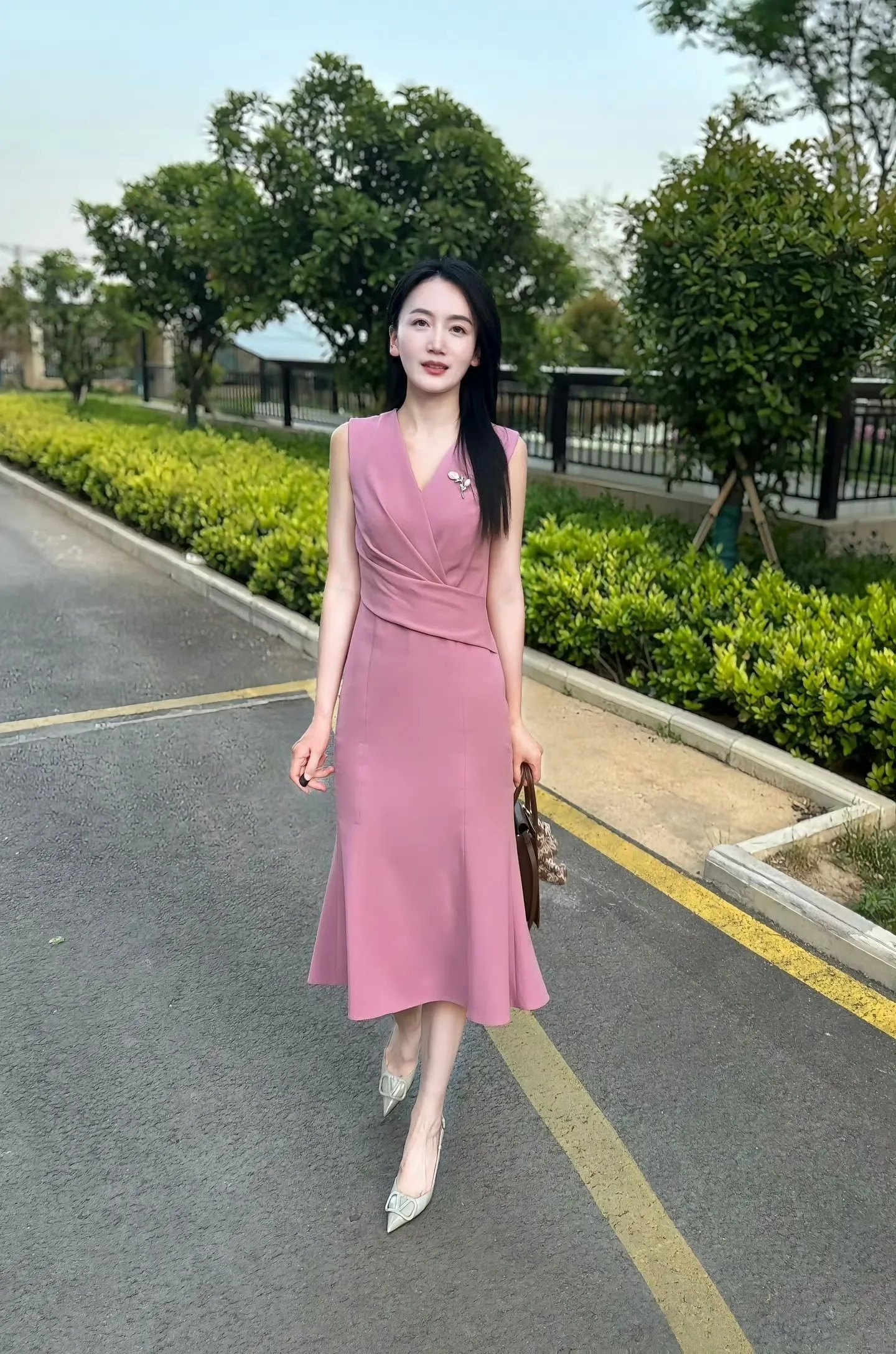 粉紫阿姨独自漫步于暖阳铺就的小径，一袭粉裙轻盈摇曳，似春日里的温柔诗篇。每一步都