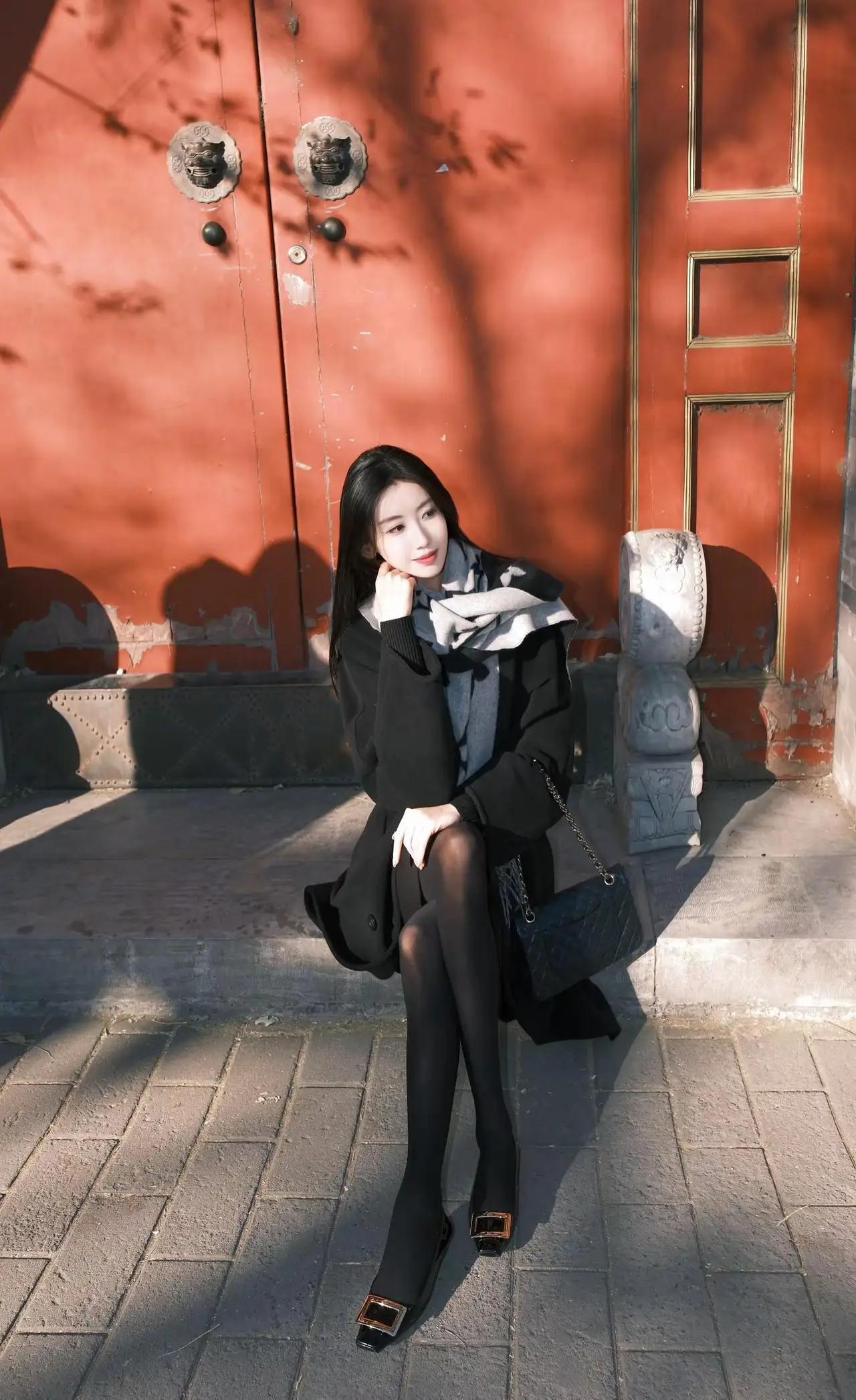 在红墙下拍照的知性美女