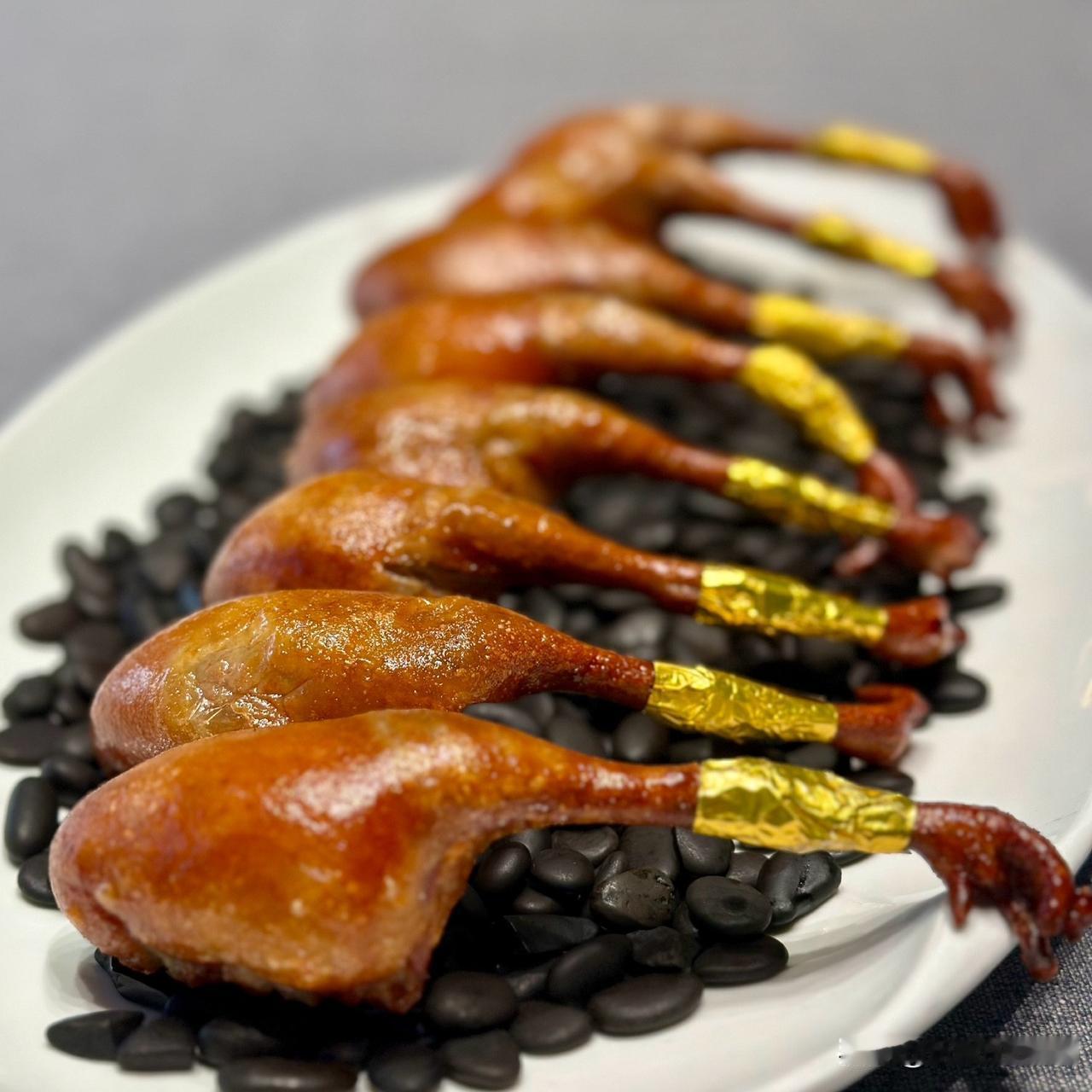 脆皮乳鸽卧在黑亮的石粒上，金黄的箔纸缠着鸽腿，泛着蜜糖般的光，咬开是肉汁漫过舌尖