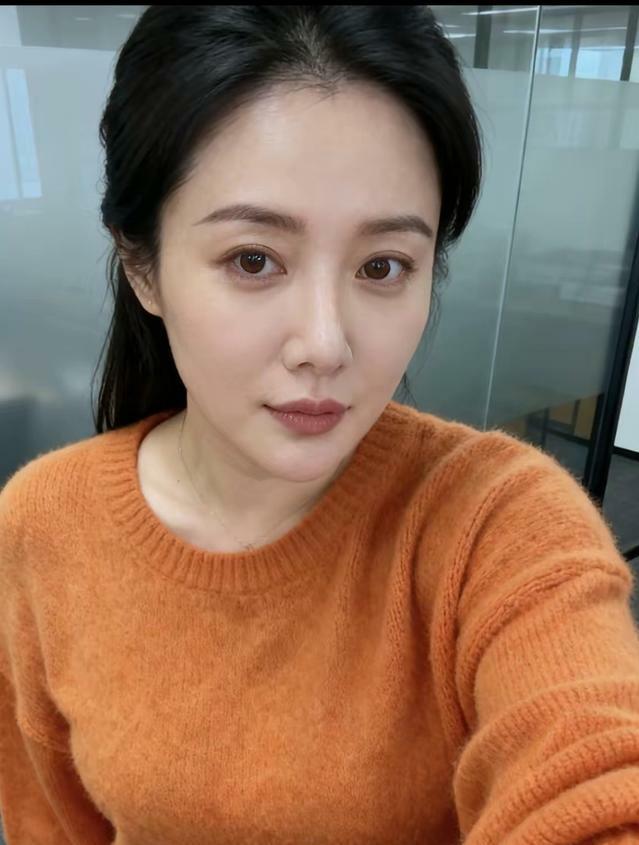 漂亮姐姐穿着橙色毛衣微笑，仿佛把夕阳穿在了身上，在阴天里做着温柔的反叛，这画面成