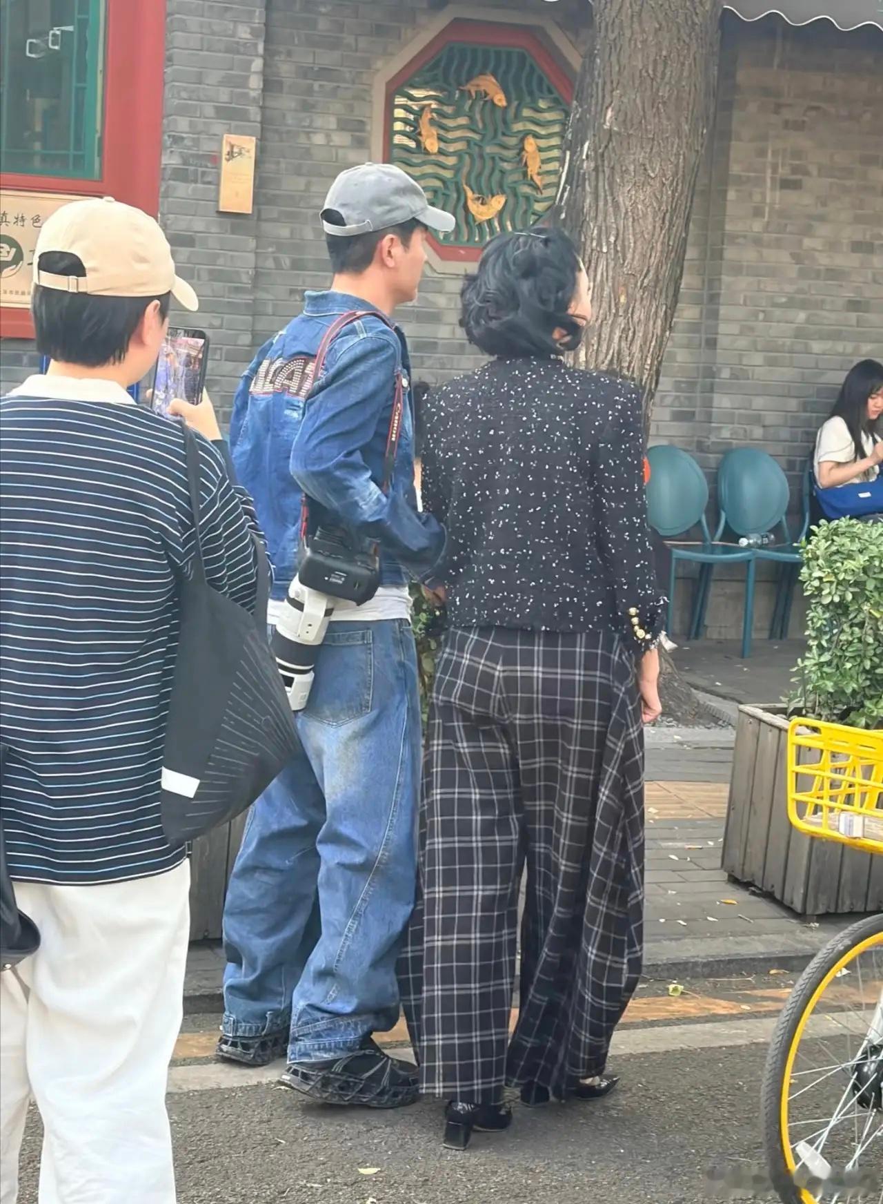 51岁郭晓东和老婆程莉莎在北京公园散步被偶遇，他背着一个长筒摄像机，在健身器械上