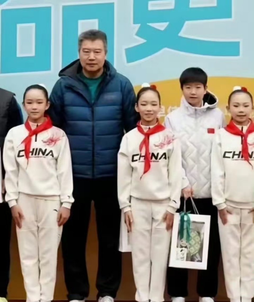 学校活动合照，孙颖莎站在李隼旁边。在李爷爷衬托下，孙颖莎小小的一只，看起来非常惹