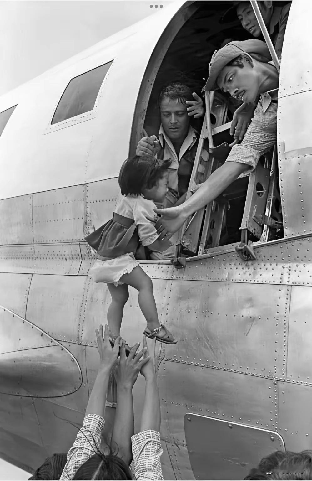 这张照片比较震撼，这是一名越南母亲把自己的孩子托举到美军的飞机上，交给了美国大兵