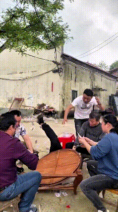 注意看！这大哥也是个急性子，瞅着街坊们围一块儿玩牌，凑过来就想挤上去看。旁