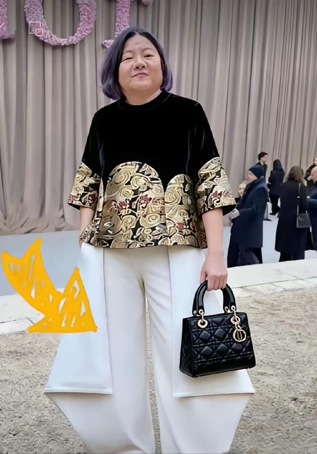 镜头中的时尚教母洪晃气质独特，一头浅紫色短发看上去洋气干练，一身锦衣华服与一个D