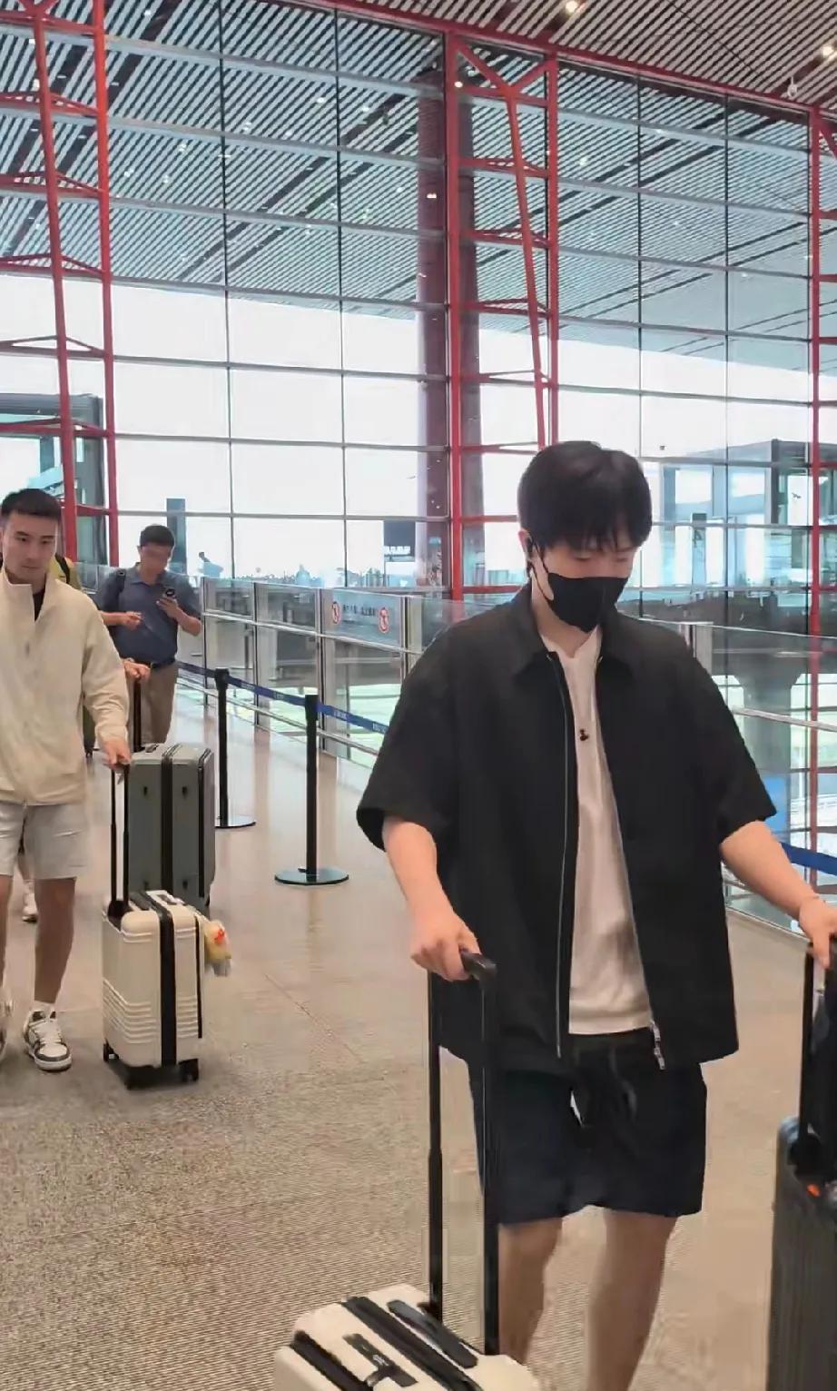 王楚钦一身黑，内搭白色短袖T恤，最显眼的是脚上的彩色涂鸦板鞋，在他身边是牛