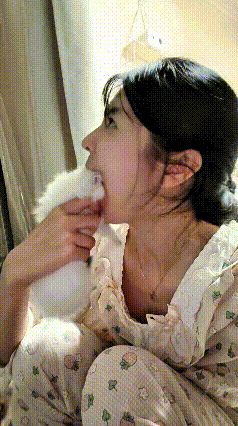 你看这个姐姐也太会逗小猫玩了，把软乎乎的小奶猫捧起来，故意往自己嘴巴边上凑着闹着