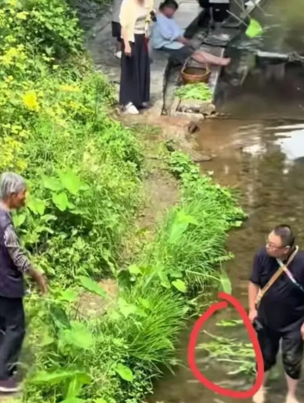 男性游客在泉水中洗脚，泉水是原住户用来淘米洗菜的，原住户的老人劝他上岸，游客不理
