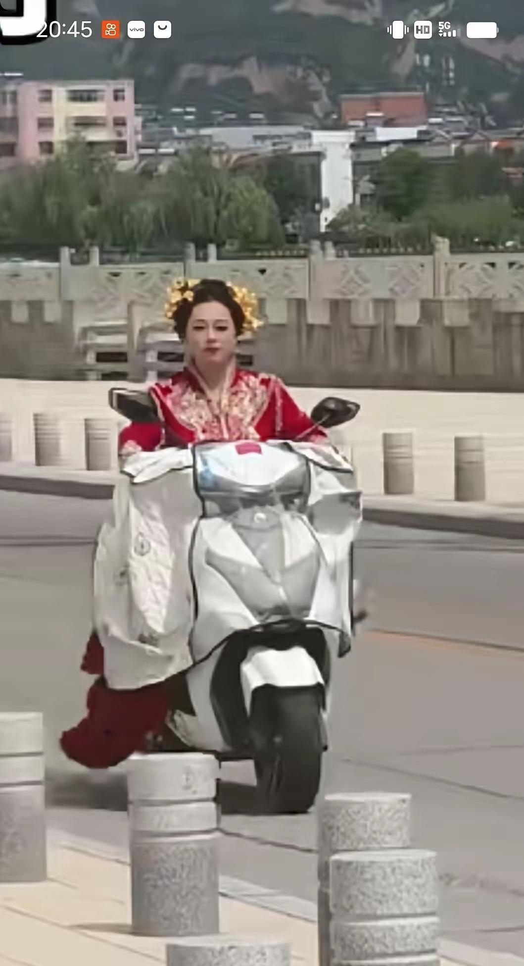 26岁新娘结婚当天没等接亲车队，自己骑电动车穿着嫁衣直奔婆家。婆婆攥着彩带站门口
