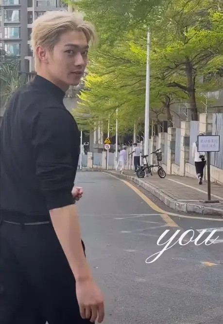 网友在爬山时遇见许凯，一身黑色套装打扮，黄发十分抢镜，期间，许凯拿着手机自拍，路