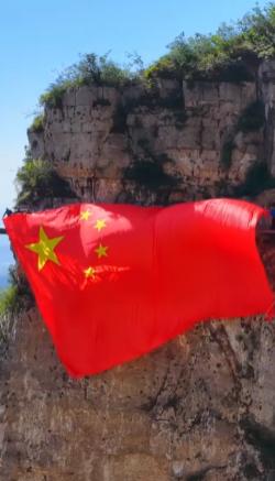 “上人民日报了！”河南云台山半山腰，游客正爬山累得喘不过气，转头撞见工作人员悬挂
