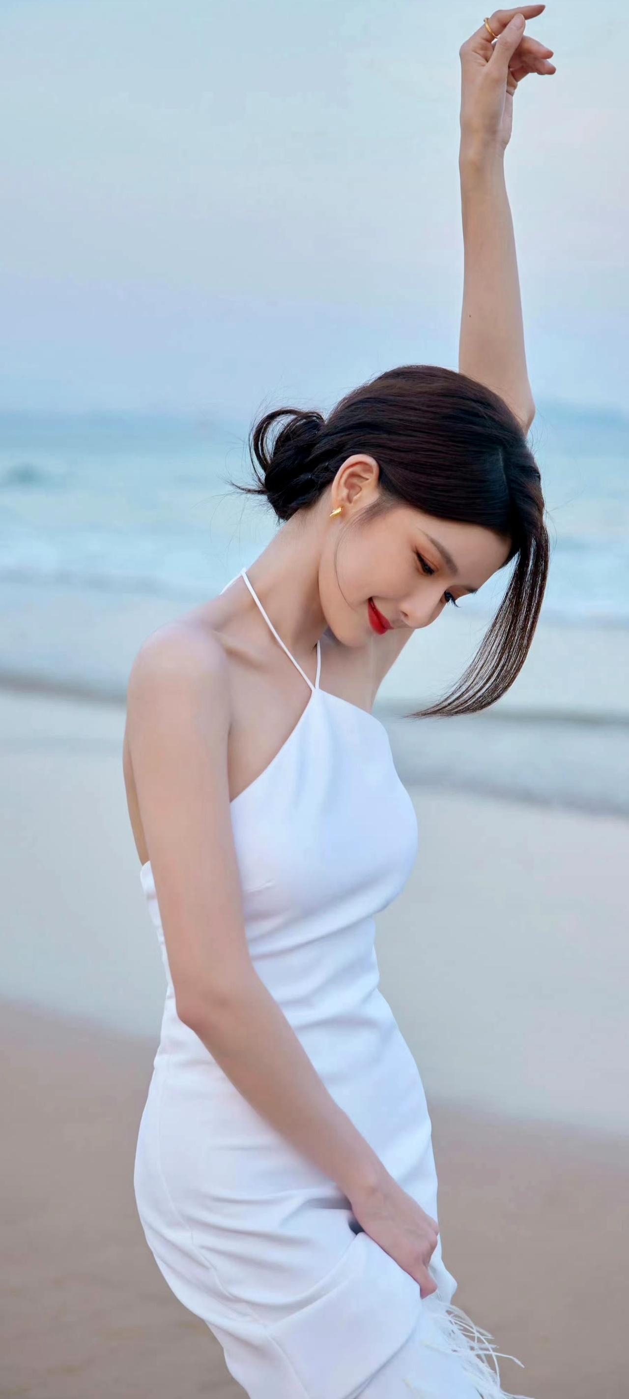 蔡卓宜白裙氛围感拉满，落日余晖下美成画！一袭白色挂脖长裙勾勒出曼妙身姿，羽毛