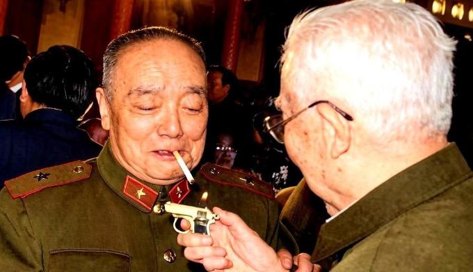 1987年新春招待会，人民大会堂灯火通明。杨尚昆穿着将官服，嘴里叼着烟。对面的王