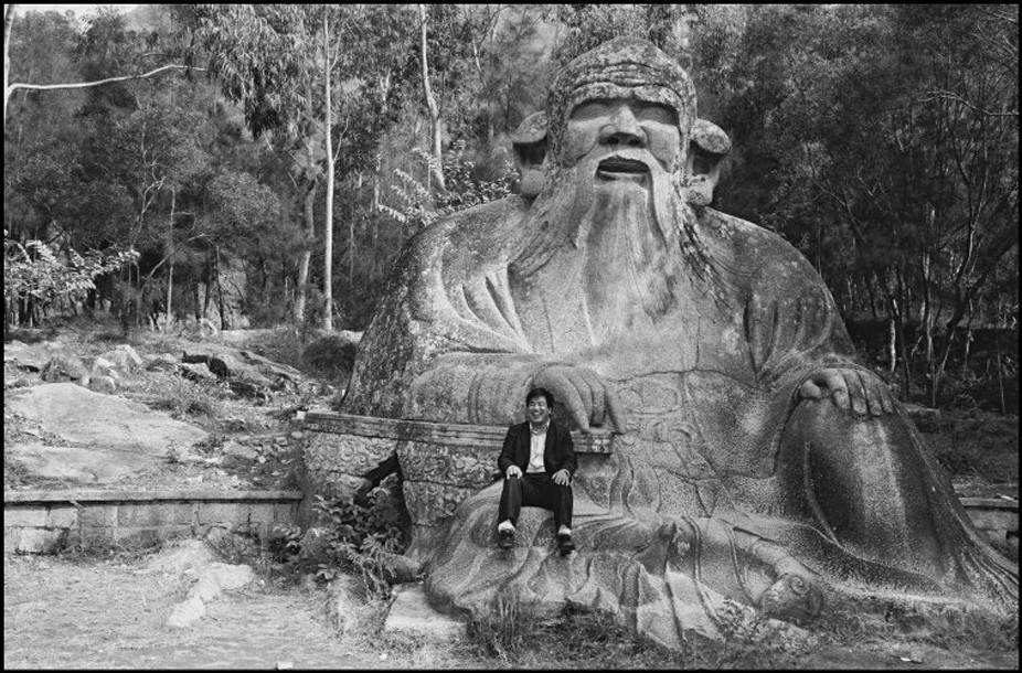 1988年，福建泉州，一位游客坐在老君岩上拍照留影。