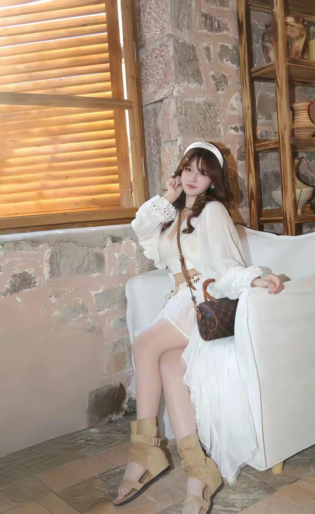 女孩坐在沙发上，穿着白色连衣裙。