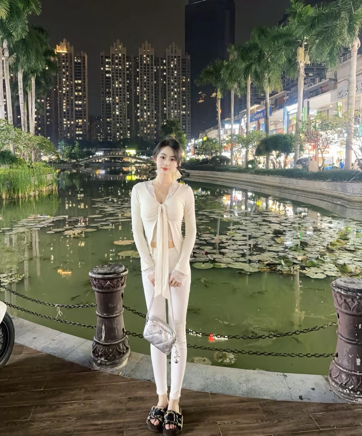 夜晚的湖畔，白衣少女与繁华都市的静谧对比。