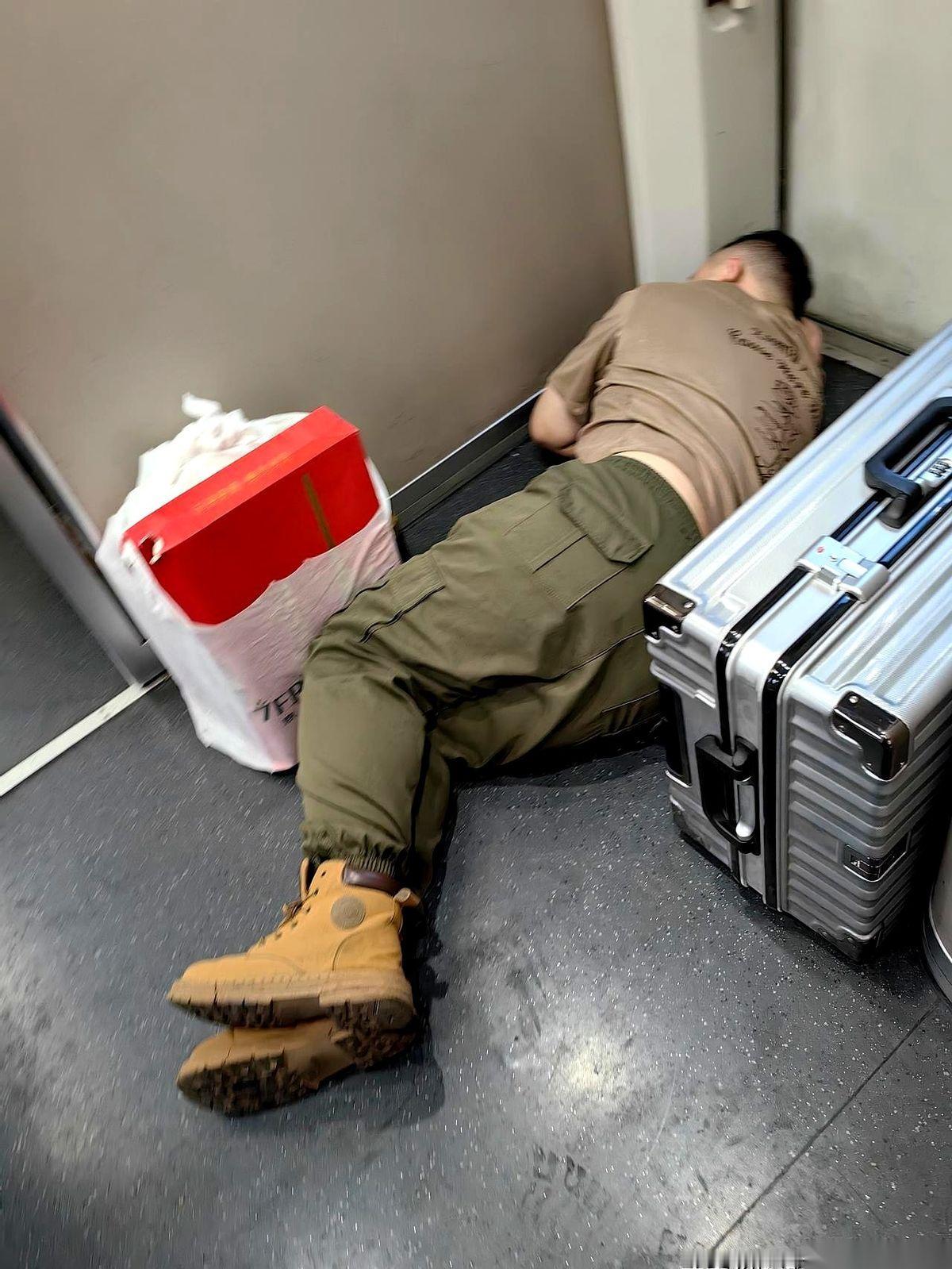 高铁车厢连接处，一个小伙子就那么直挺挺地躺下了。旁边就是厕所，人来人往，一双双