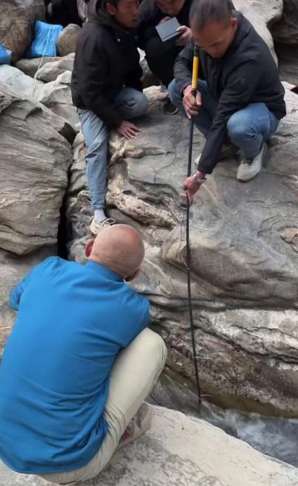 几名男子在山上的小溪里游泳，一名男子发现一块巨大的石头下面一条缝隙和一处水洞相连