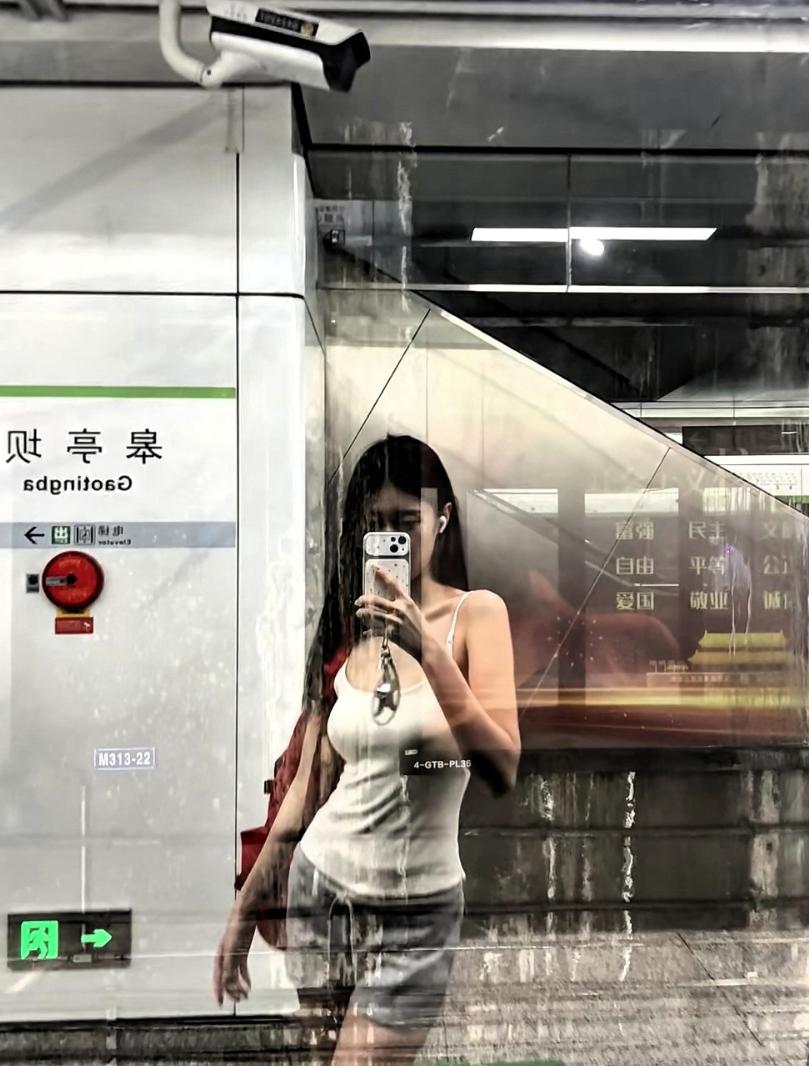 杭州这次又火了！一名小姐姐穿着吊带在地铁站等车，期间就对着玻璃拍了两张照片，这时