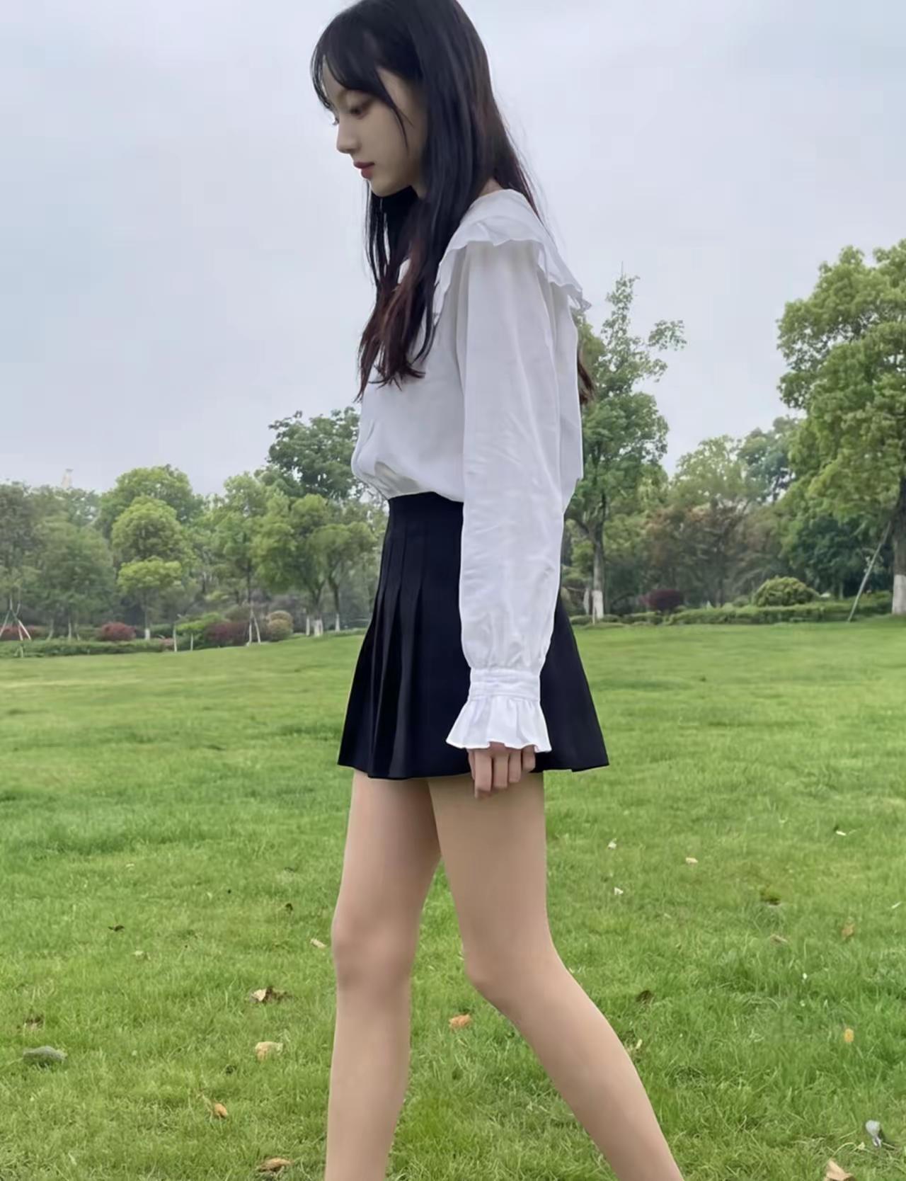 校园少女漫步绿茵，白衬衫与黑短裙的清新搭配，尽显青春活力！🌿👗👠坚持健身锻