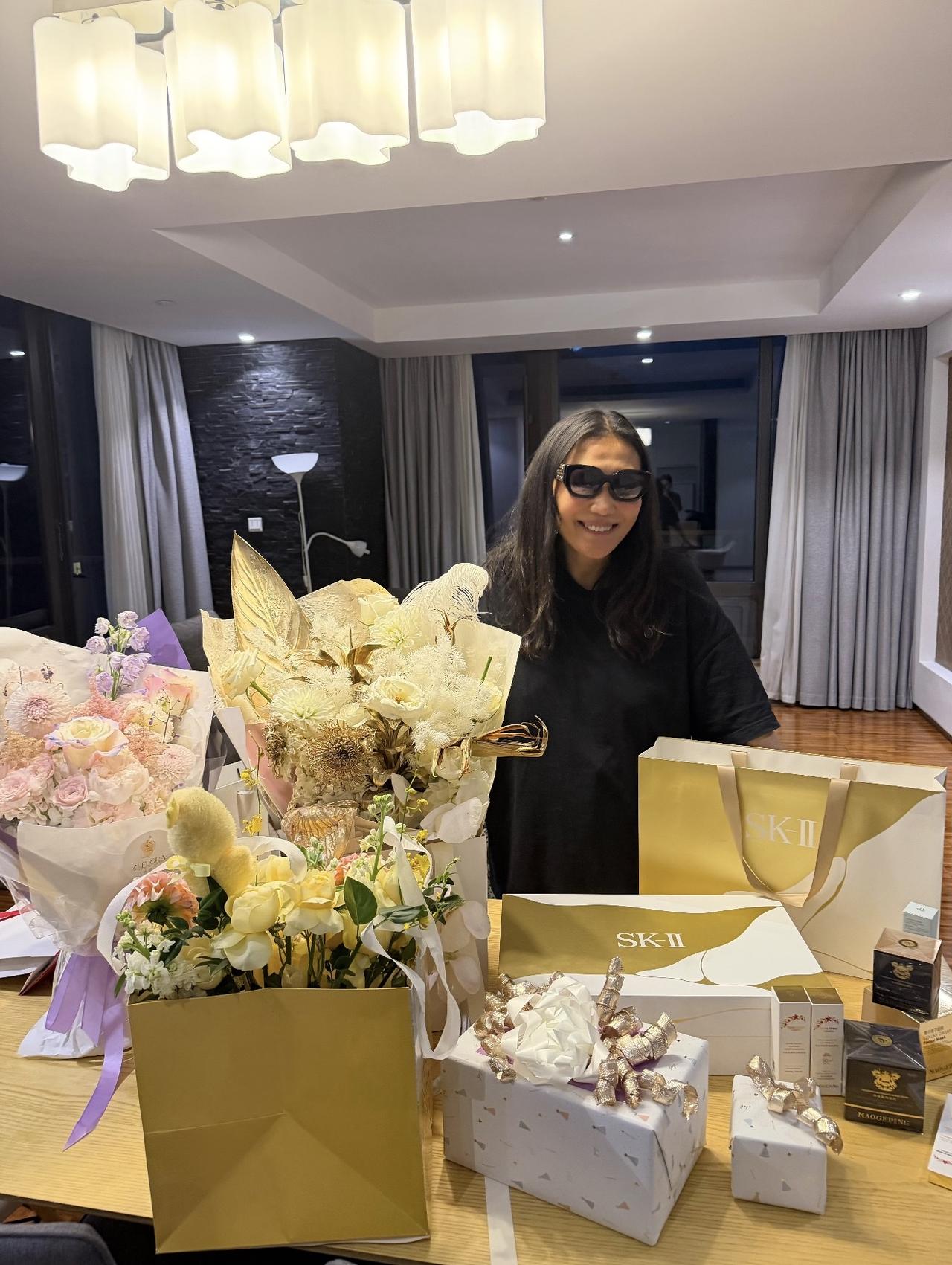 谷爱凌晒照为妈妈庆祝生日，谷燕素颜在家中拍照，面前有三束鲜花和礼物，家里装修的好
