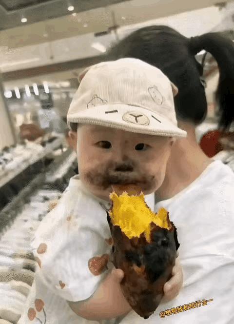 一个宝宝在妈妈怀里吃烤红薯，弄的嘴巴鼻子都乌黑，他自己又看不见，还吃的津津有味。