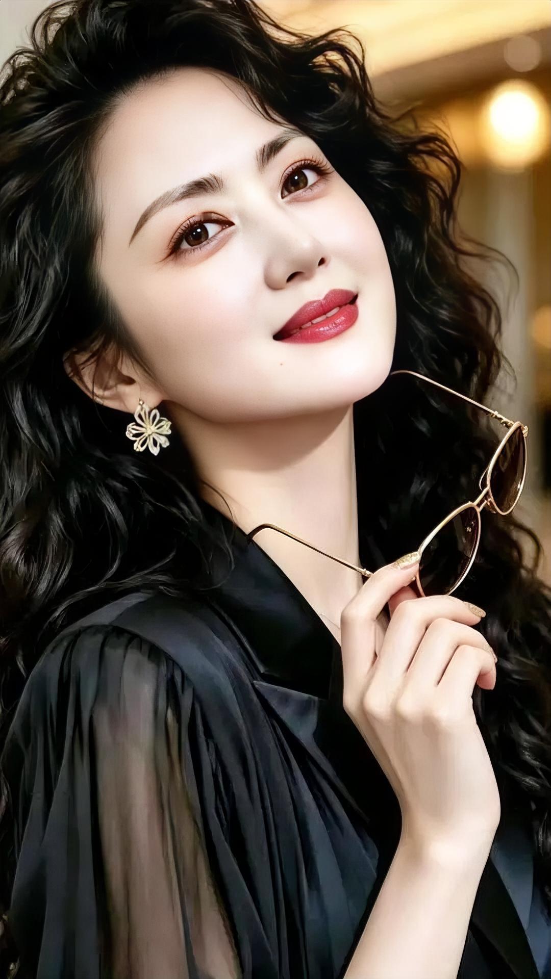 卷发如风轻扬，笑意落在唇上。墨色衣衫温柔荡，指尖轻握暖光。耳畔花