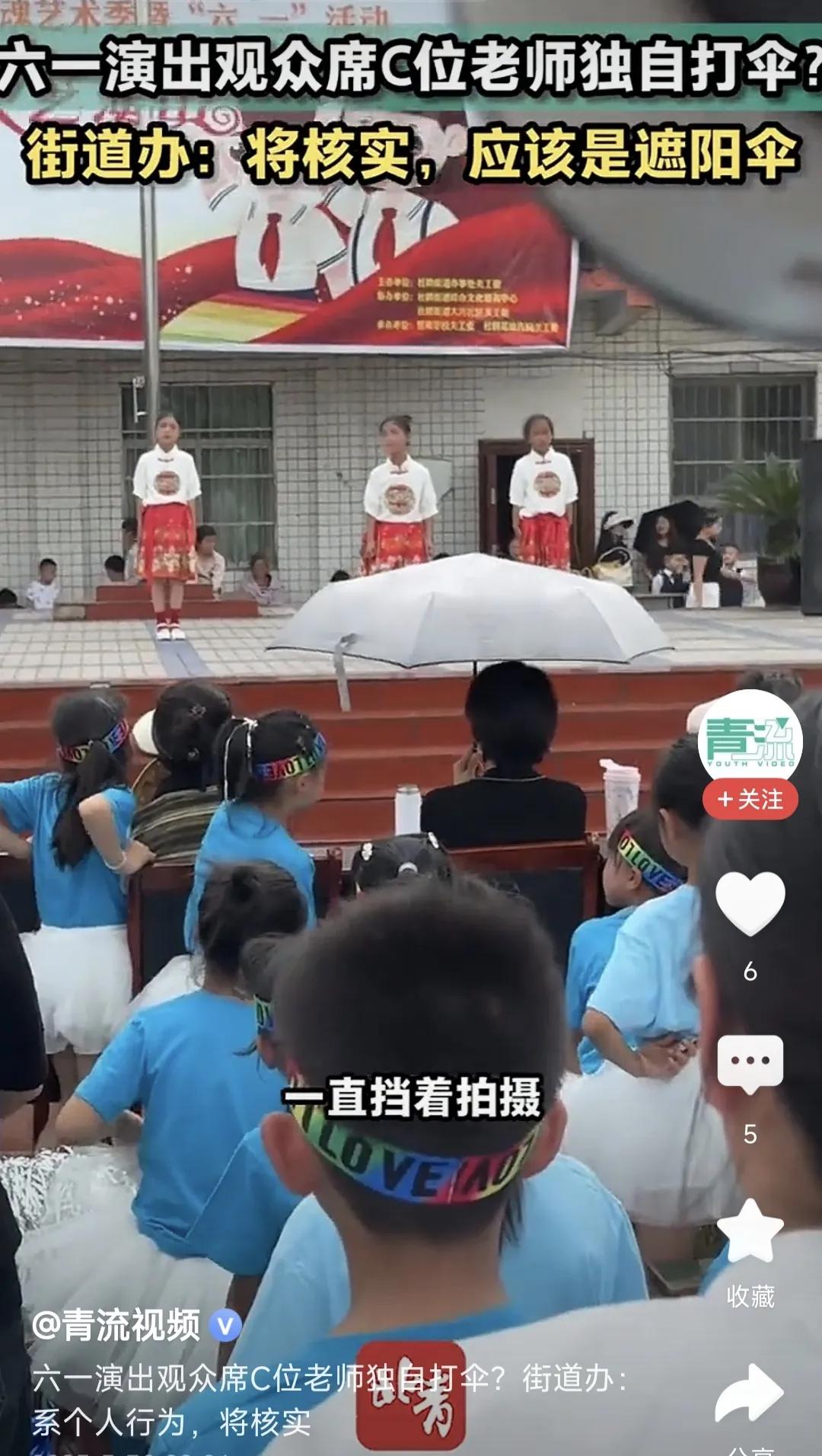贵州黔西某街道办六一儿童节演出现场，坐在C位的老师撑着伞看比赛，后面的人多次提醒