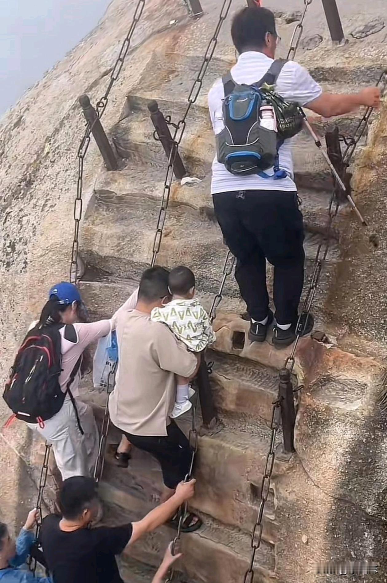 抱着小朋友去登山，没有任何防护措施，这也太危险了