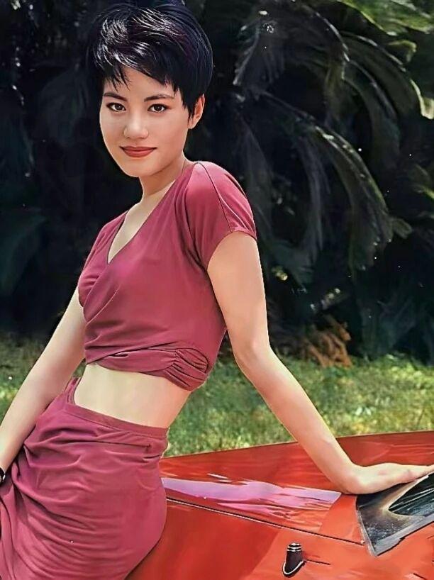 王菲90年代的红衣装扮好妖娆，外形和样貌酷似当年的陈宝莲。她一头干练短发，酒红色
