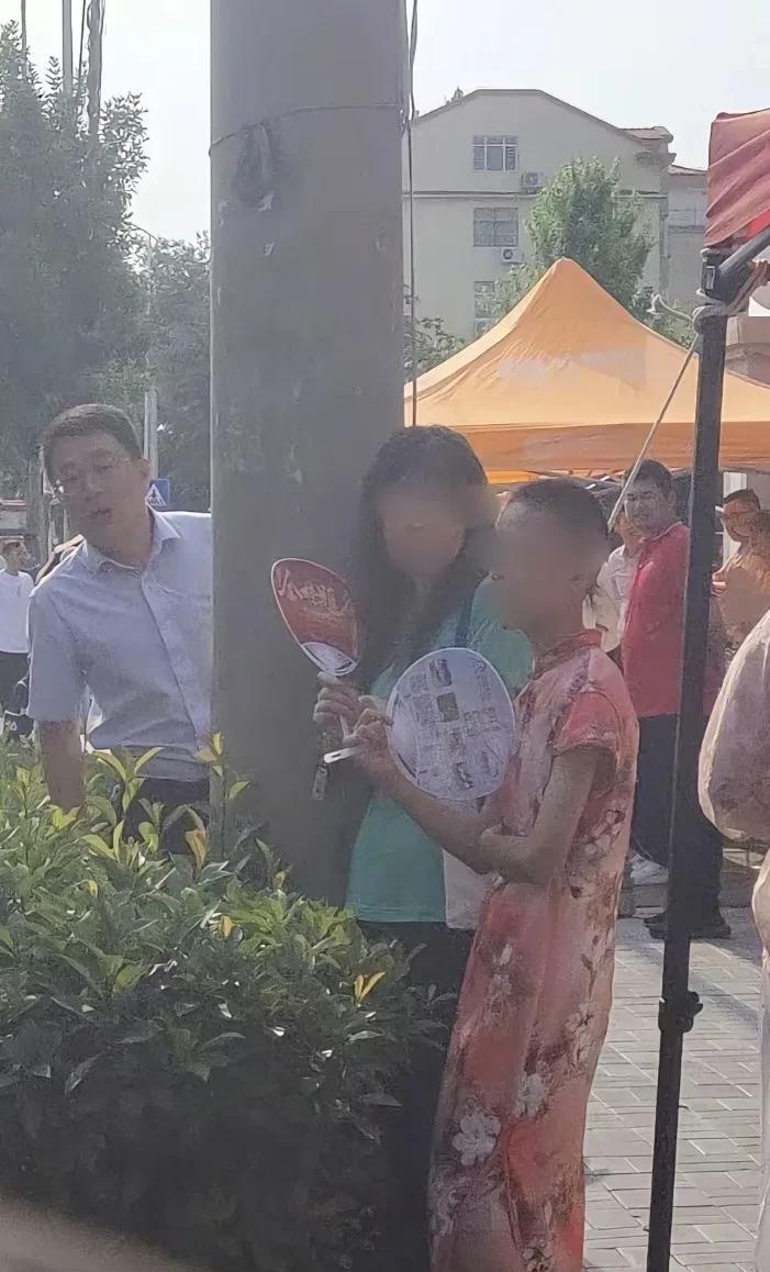 今天一对母子一出现学校门口，瞬间吸引了大批家长们的围观，只见一个瘦瘦的考生男孩，