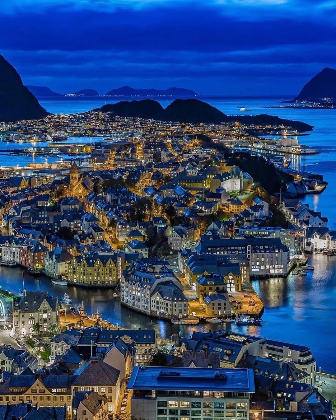 这是挪威奥勒松的夜景，被誉为最美峡湾城市。照片在一月中午拍摄，展现了独特的蓝色时