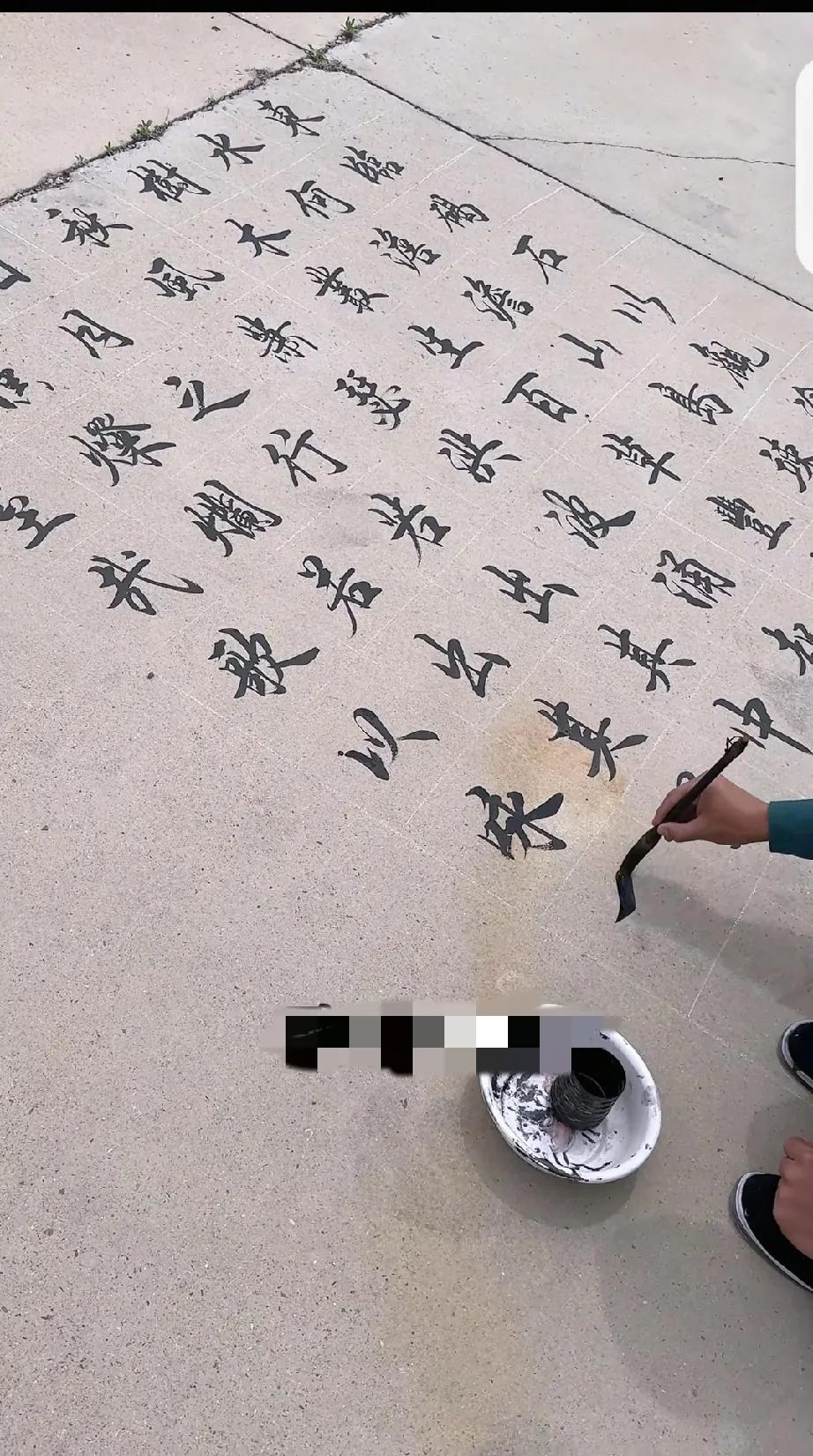 一位农民工大哥在户外的地上写字，行楷书写得非常规范，水平不输专业的书家。现在难得