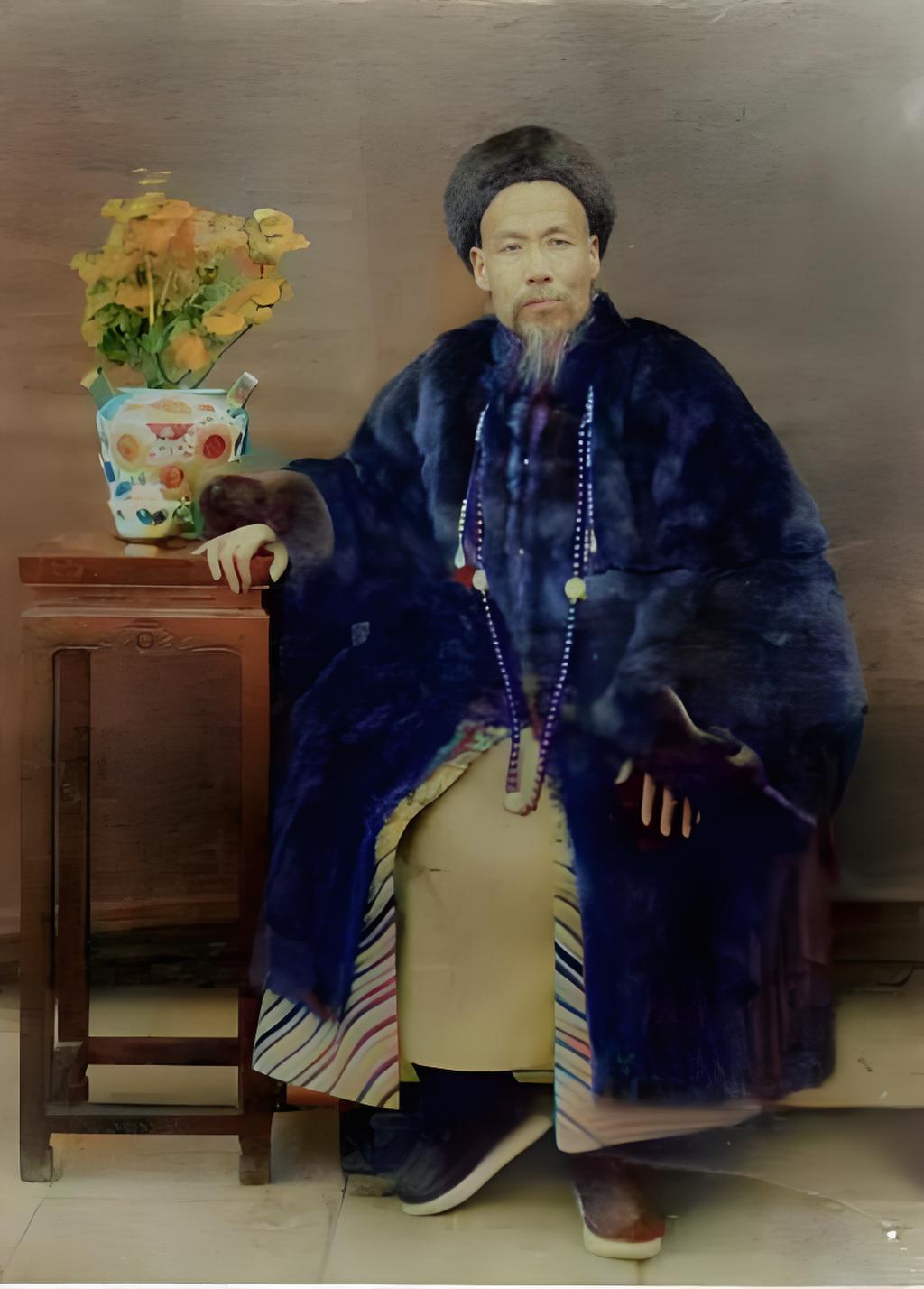 照片里，曾纪泽身着厚重的皮裘，头戴暖帽，颈挂朝珠，神态沉稳，端坐在椅子上，左手搭
