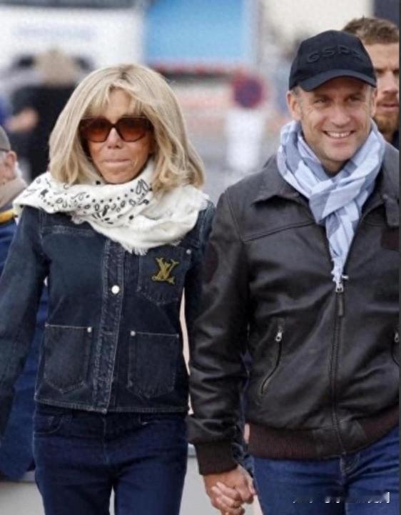 照片中的布丽吉特穿着自己最爱的LV牛仔外套，下身一条休闲裤配运动鞋。旁边马克龙