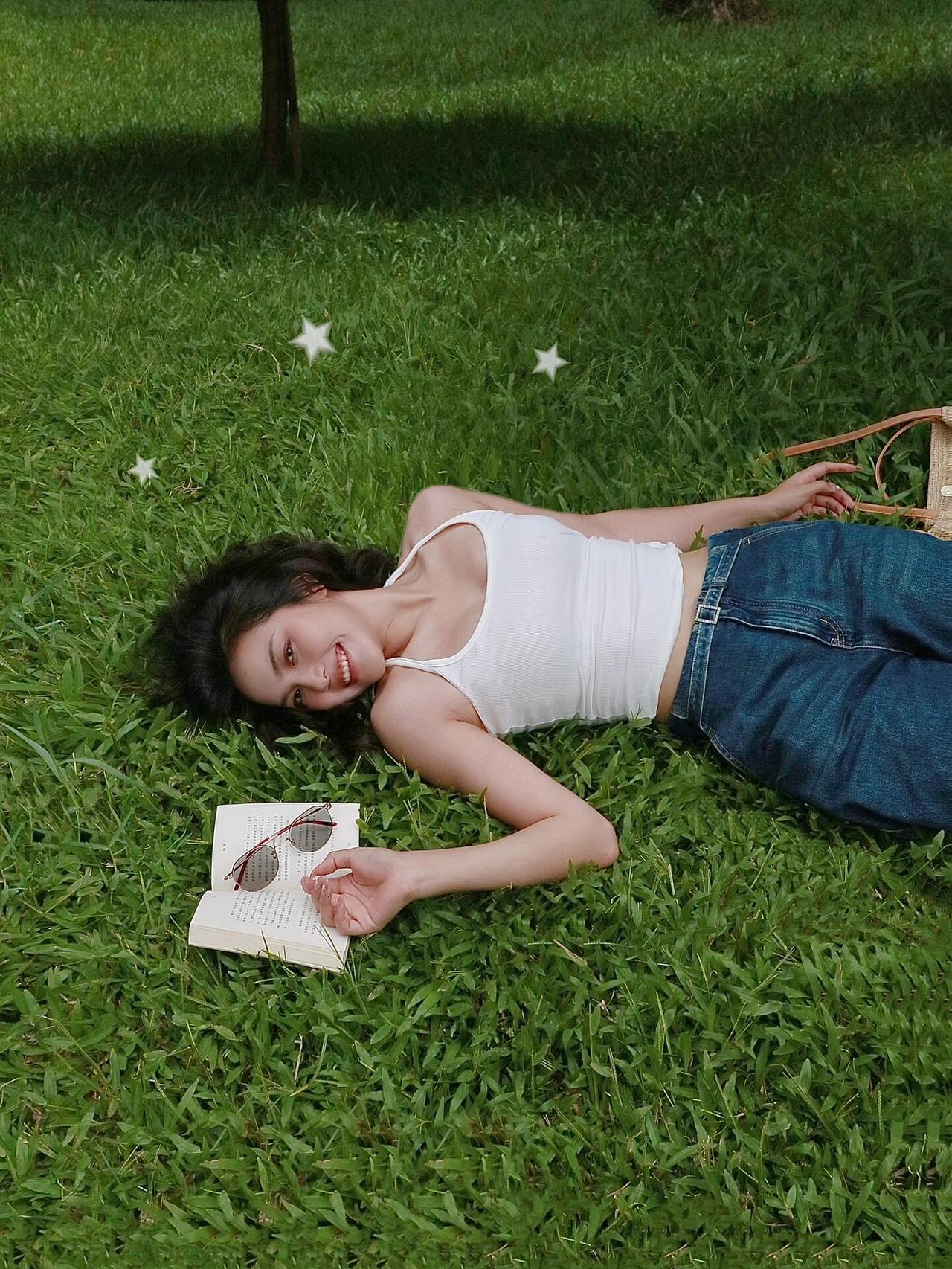 草木间的松弛白背心裹着盛夏的风，落进草地的柔软里她躺着，发丝漫过青草地