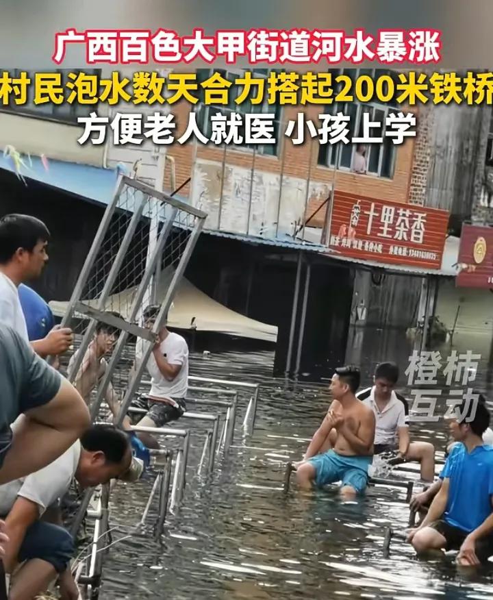 河水淹没街道数天，村民搭建200米铁桥，网评却跑偏了。广西百色大甲街道被河水淹