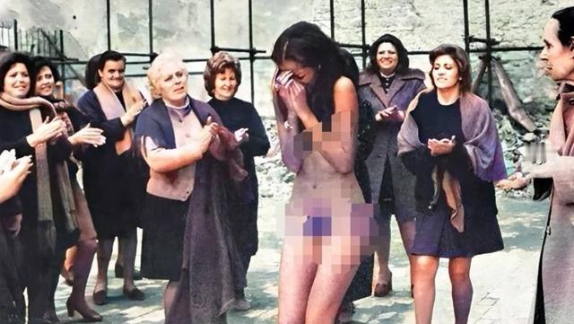 1945年，一名法国女人被剃光头发、脱光衣服后游街。她的周围，不时有人指指点点，