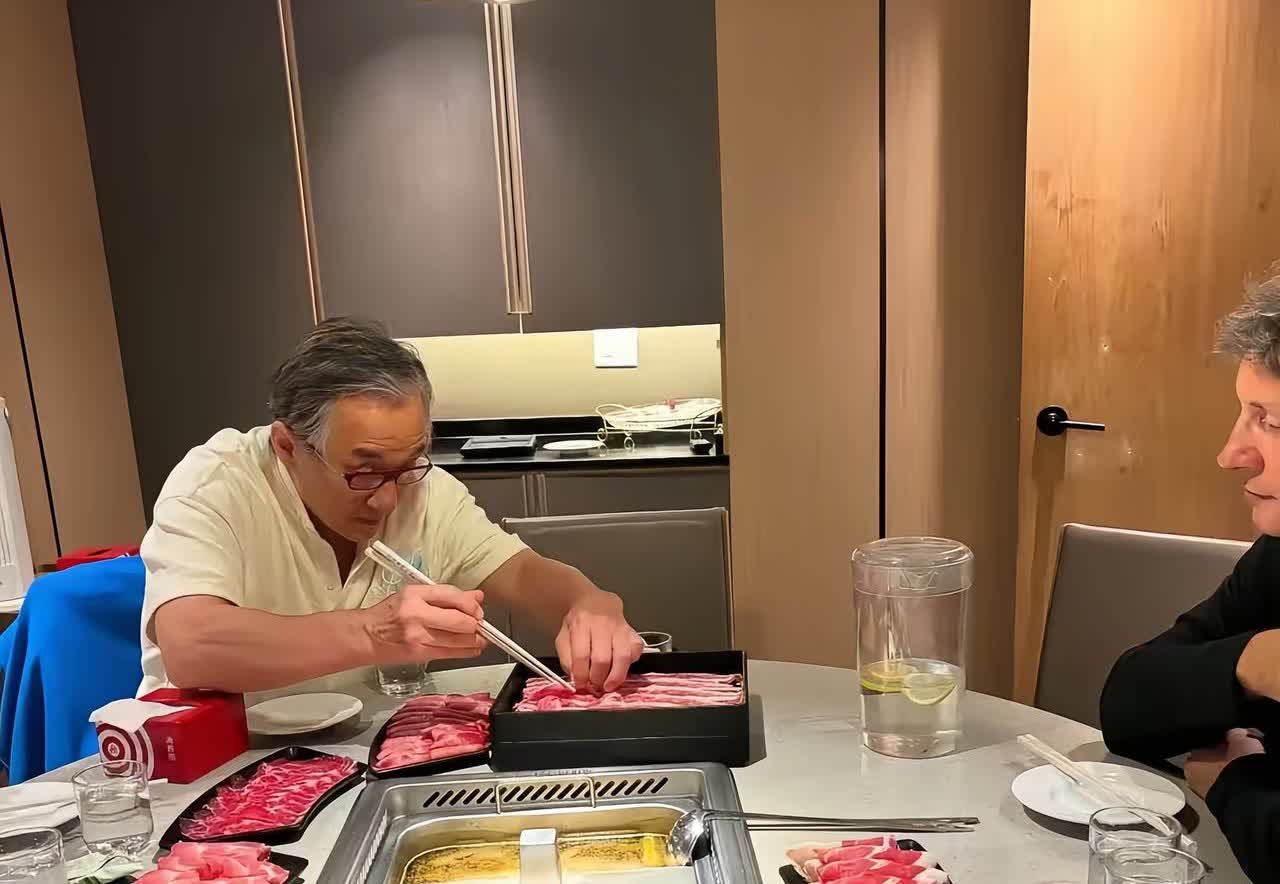 成龙大哥涮火锅的画面，他两鬓斑白，戴着一副眼镜，用筷子夹着盘子里的肉卷，人苍老了
