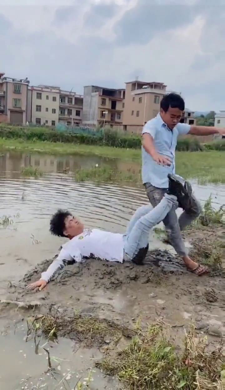 田间趣事：两位朋友在水田里欢快地玩耍搞笑