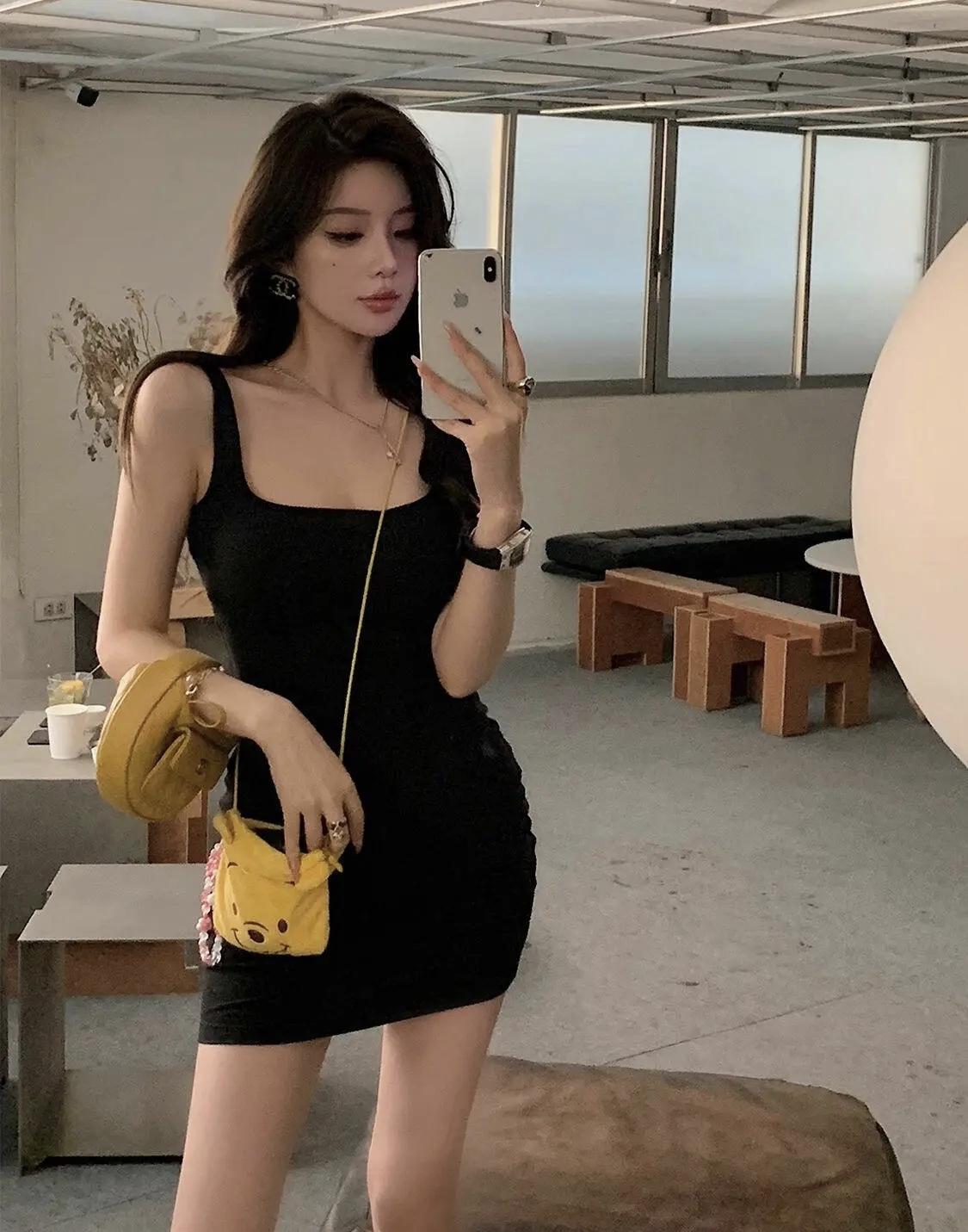 小黑裙的利落线条，被明黄包包点亮了整个穿搭。简约的室内空间里，松弛与精致刚好撞了