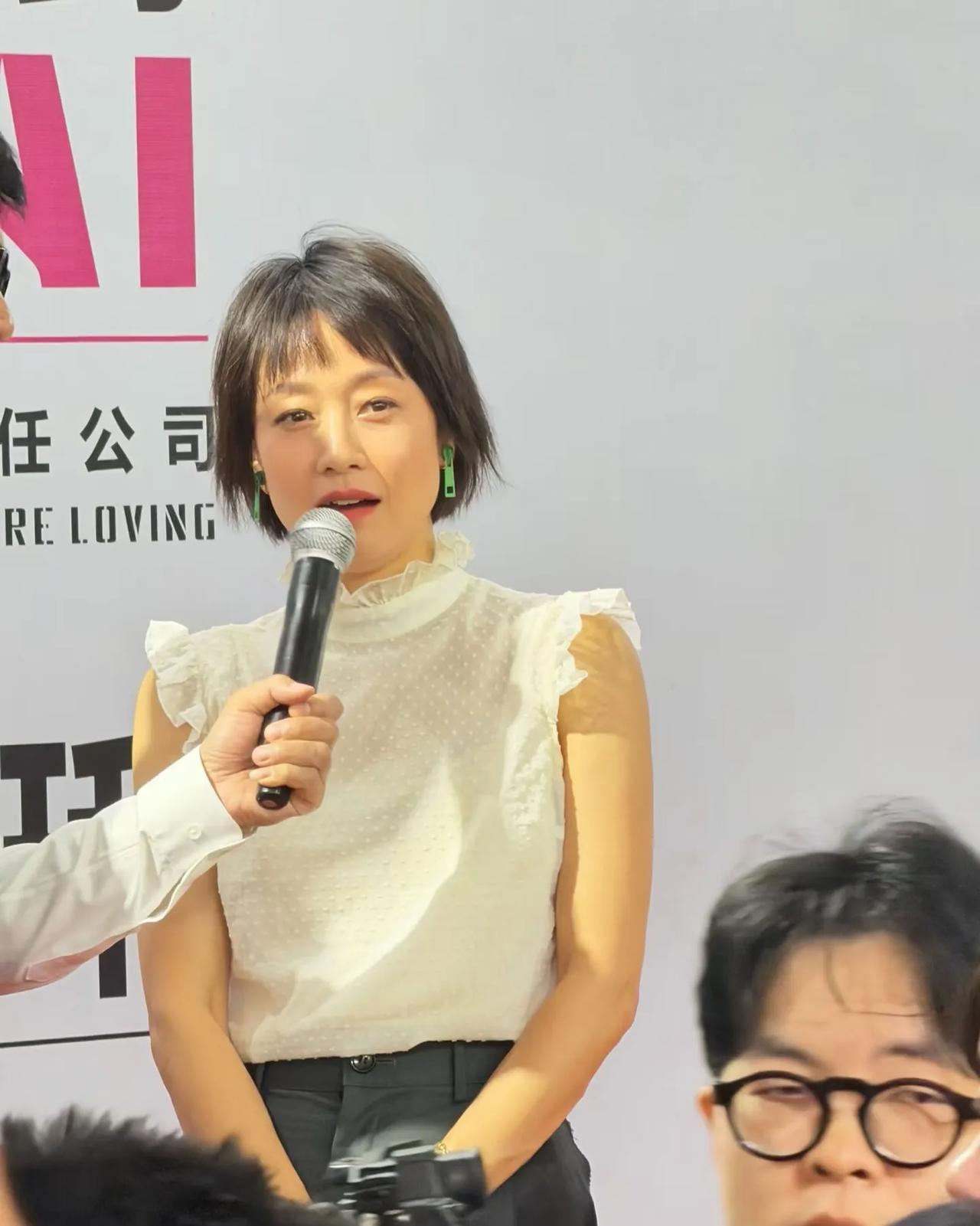 马伊琍在上海参加品牌线下活动，穿了一件白色的荷叶边无袖上衣，特意戴了一对绿色