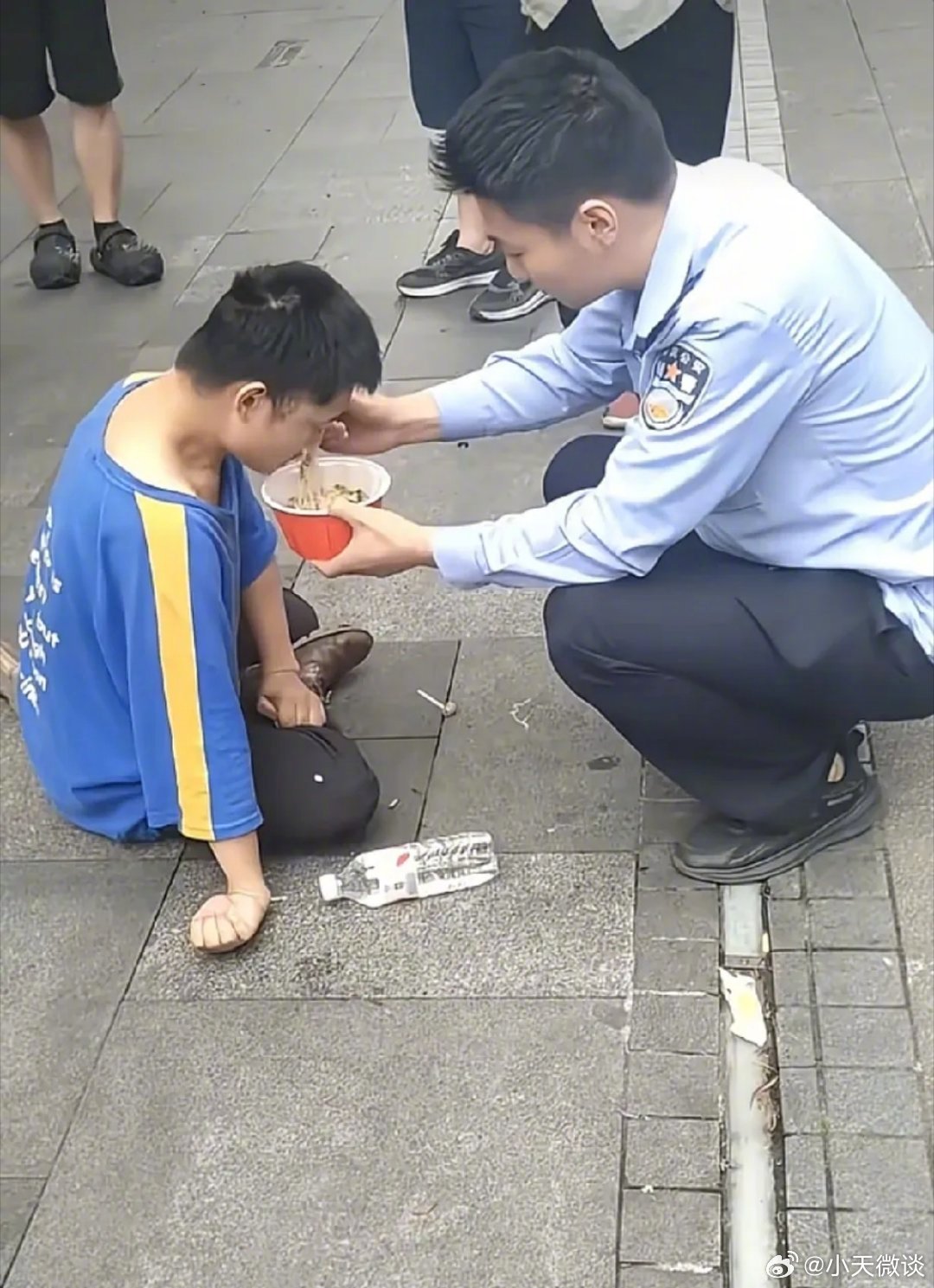 暖心！街边人行道上，一名残疾小伙子坐在地上，四下张望过往行人。路人匆匆而过，无人停留。这时，一名年轻