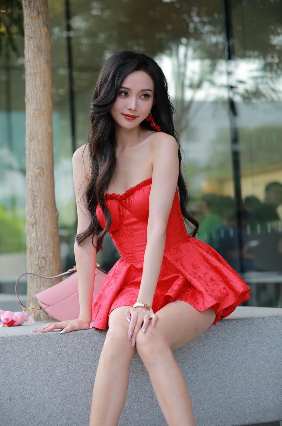 正红抹胸裙裹着缎面的柔，裙摆的褶皱漾着甜，往石阶上一坐，松弛的姿态把艳揉成了夏意